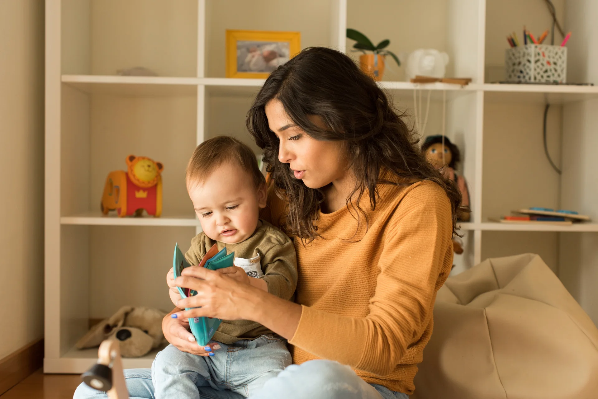 A woman is sitting on the floor with a baby on her lap.