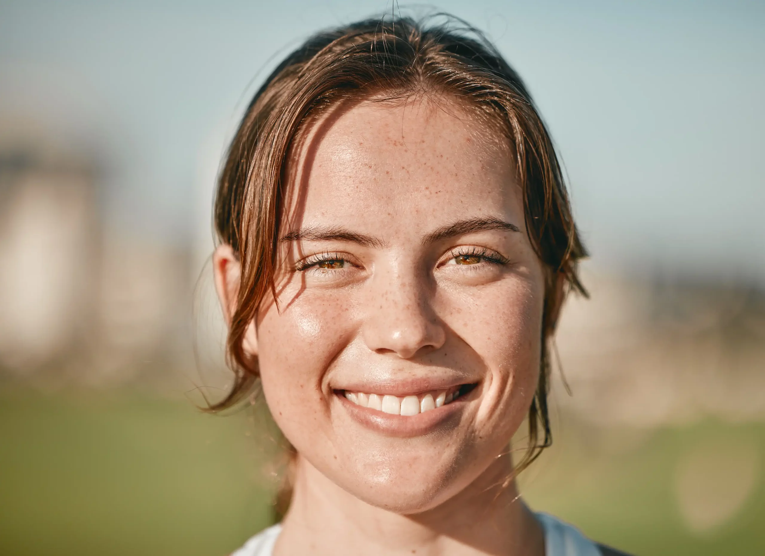 A close up of a woman smiling in a park.